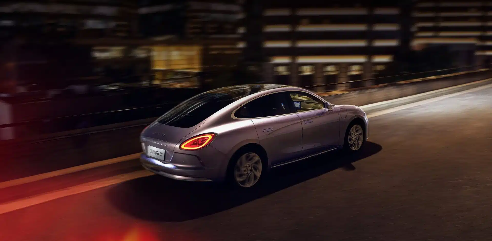 GWM ORA 07 fährt bei Nacht durch die Stadt, Rückansicht des Elektroautos mit markantem Design.