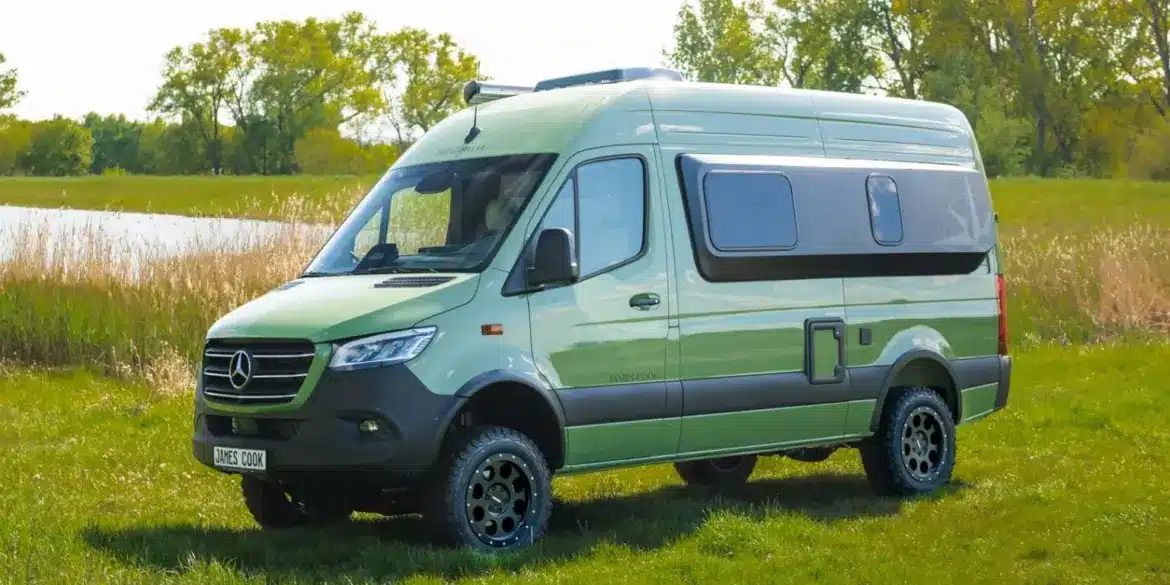 Grüner Westfalia James Cook 600 D Kastenwagen auf Mercedes Sprinter Basis steht auf einer Wiese vor Bäumen und einem See.