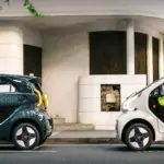 Zwei XEV YOYO PRO Stadtautos in verschiedenen Farben auf einer Straße vor einem Gebäudeeingang
