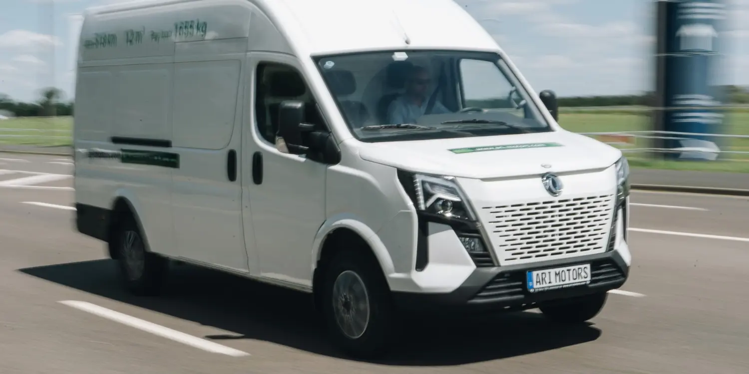 Weißer ARI 1710 Elektro-Transporter fährt auf einer Landstraße bei Tageslicht.