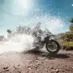 Benelli TRK 502 X fährt durch eine Wasserpfütze auf einer Schotterstrecke im Gelände.