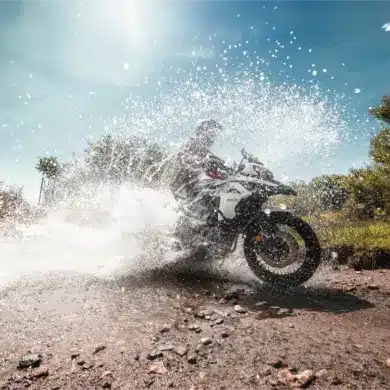 Benelli TRK 502 X fährt durch eine Wasserpfütze auf einer Schotterstrecke im Gelände.