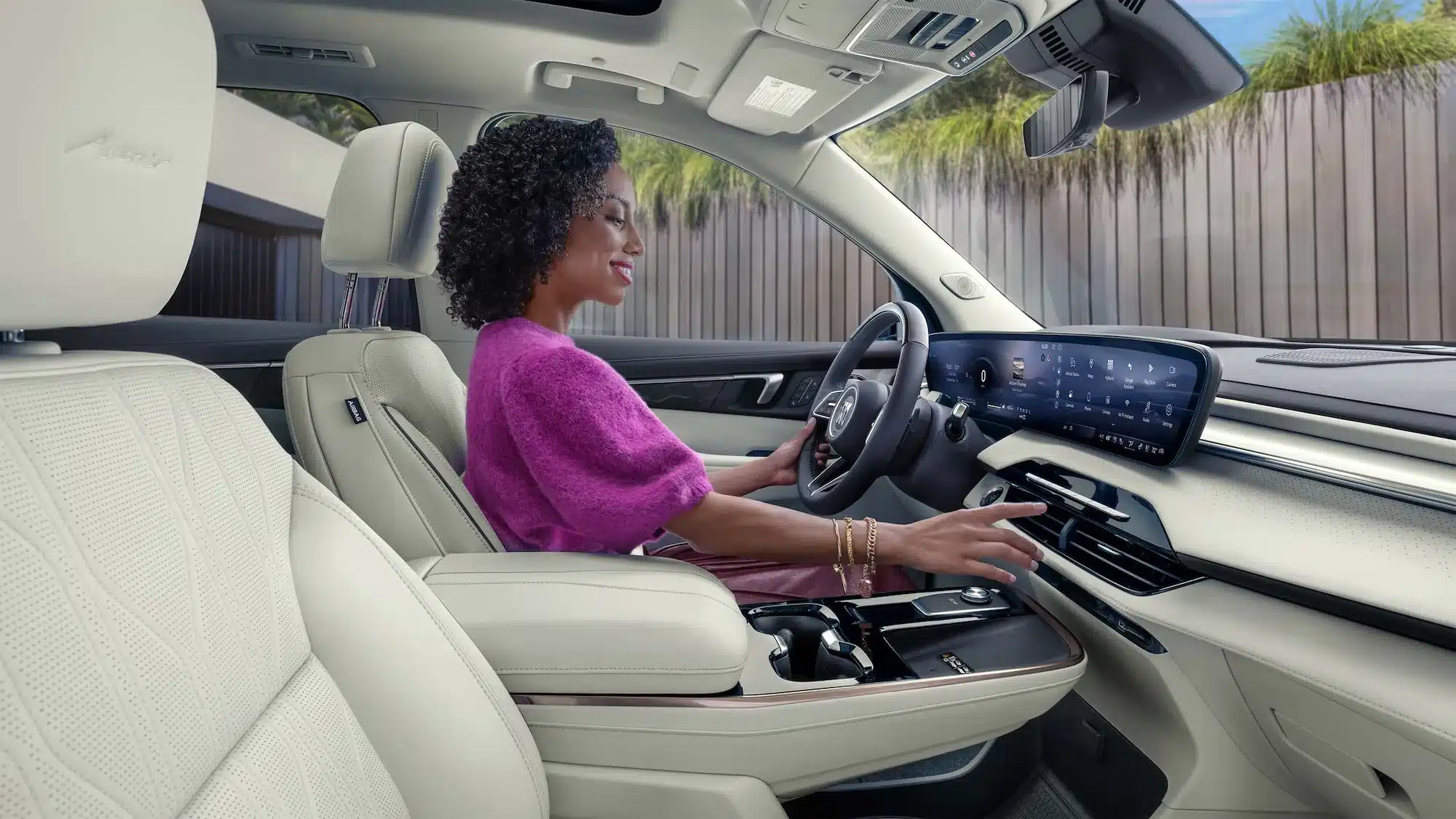 Fahrerin sitzt im luxuriösen Innenraum des Buick Enclave Avenir mit großem Digital-Display und hellen Ledersitzen.