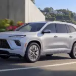 Buick Enclave Avenir 2025 fährt auf einer modernen Straße entlang, Seitenansicht des Fahrzeugs.