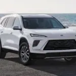 Buick Enclave 2026 in Weiß von vorn am Meer geparkt.
