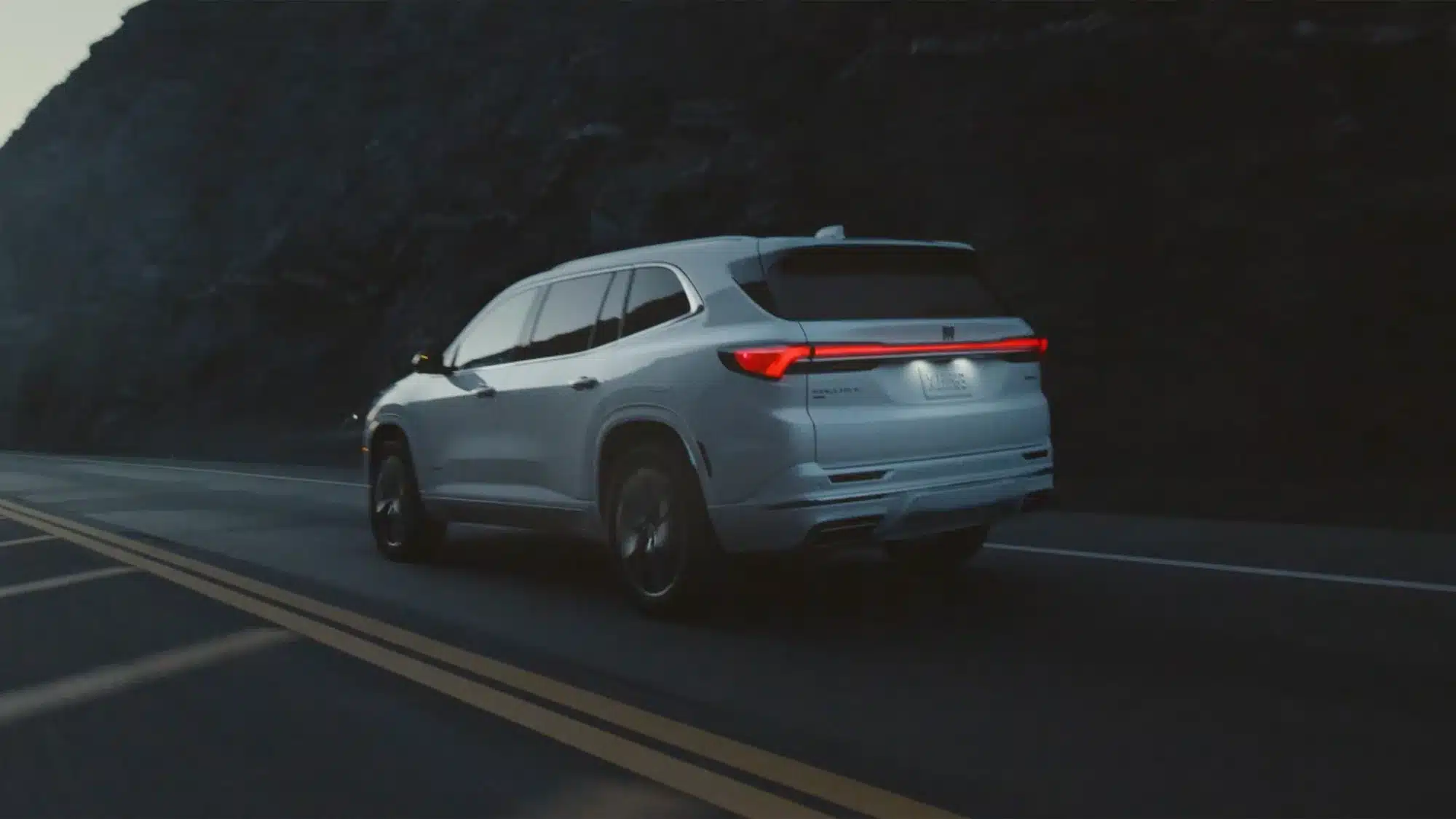 Rückansicht des 2026 Buick Enclave auf einer Landstraße bei Dunkelheit
