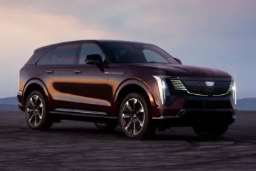 Cadillac Escalade IQ, großes elektrisches SUV in Dunkelrot auf offenem Asphalt bei Sonnenuntergang