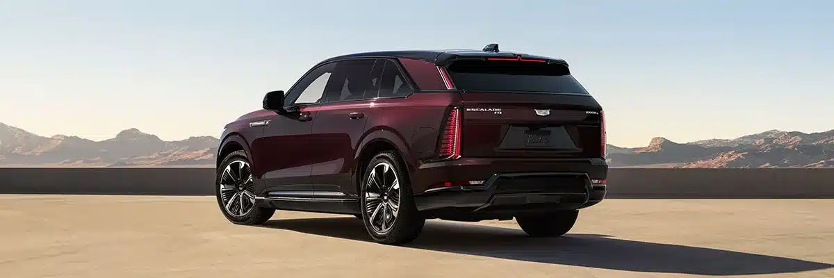 Heckansicht des Cadillac Escalade IQ in Bordeauxrot auf einem Parkdeck mit Bergkulisse im Hintergrund