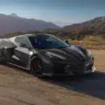Schwarze Chevrolet Corvette Z06 vor Berglandschaft bei Sonnenaufgang auf einer Landstraße.