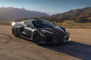 Schwarze Chevrolet Corvette Z06 vor Berglandschaft bei Sonnenaufgang auf einer Landstraße.