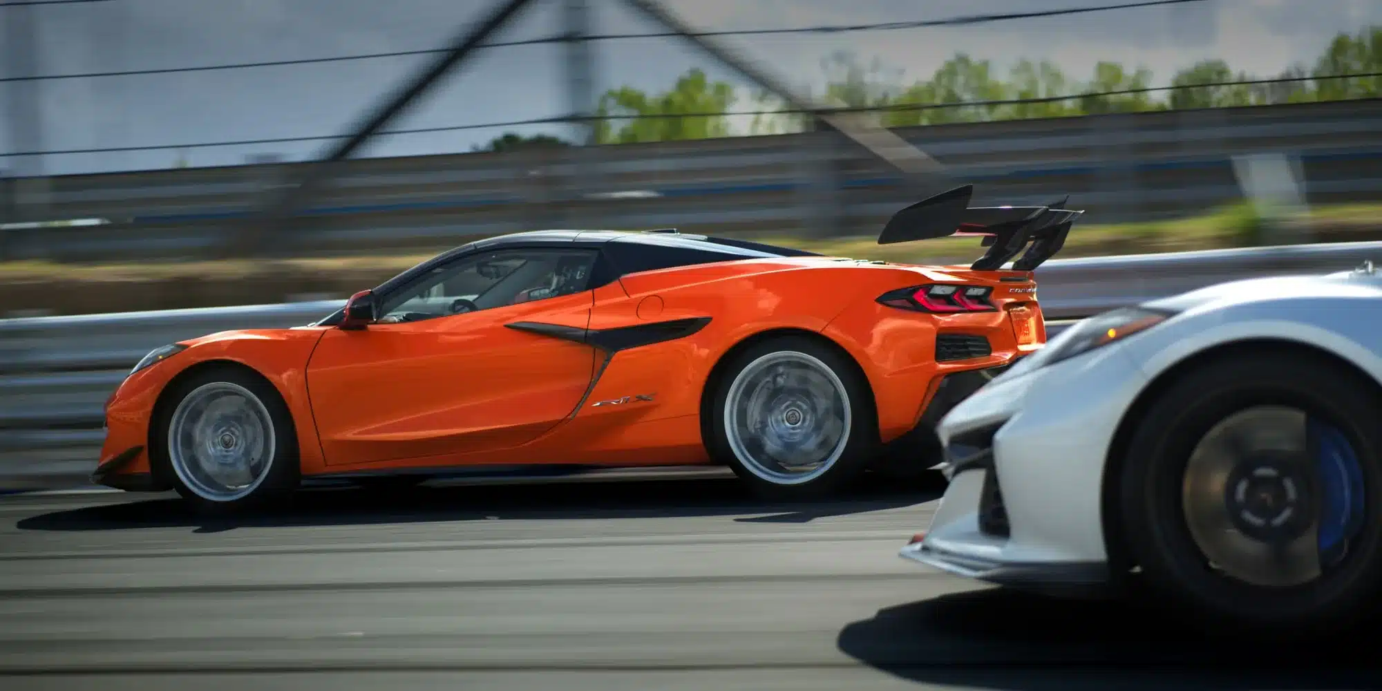 Orangefarbene Corvette ZR1X und weiße Corvette Z06 im Renntempo auf der Strecke