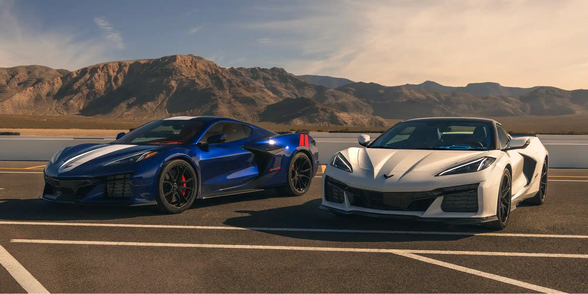 Zwei moderne Chevrolet Corvette C8 in Blau und Weiß vor einer Gebirgskulisse auf der Rennstrecke