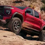 Roter GMC Canyon AT4X 2026 fährt über felsiges Gelände mit ausgeprägter Offroad-Optik.