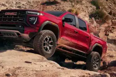 Roter GMC Canyon AT4X 2026 fährt über felsiges Gelände mit ausgeprägter Offroad-Optik.