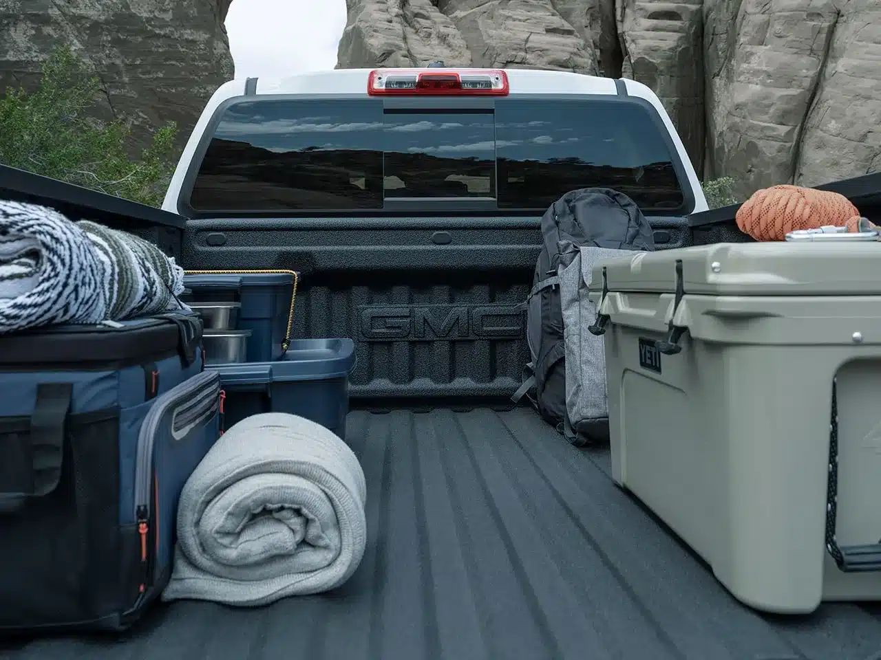 Blick auf die beladene Ladefläche eines GMC Canyon 2026 mit Camping- und Outdoor-Ausrüstung.