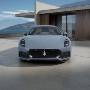 Frontansicht des Maserati GranTurismo Folgore in Hellgrau vor moderner Architektur und Meereshintergrund.