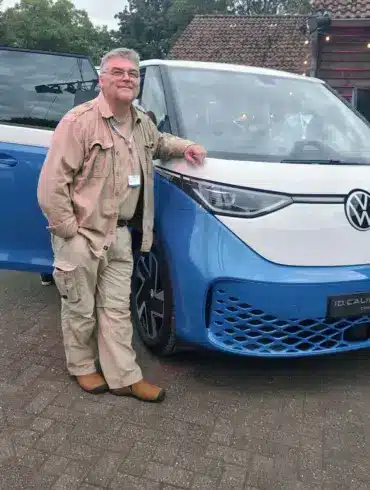 Person steht vor dem Volkswagen ID. California Cruise Campervan, fotografiert bei Tageslicht
