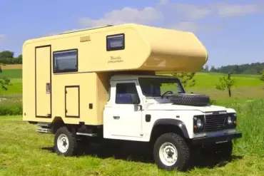Landrover Offroad-Camper mit wintertauglichem GFK-Aufbau auf einer Wiese