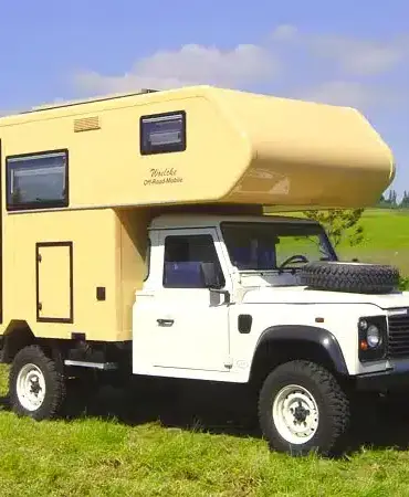 Landrover Offroad-Camper mit wintertauglichem GFK-Aufbau auf einer Wiese