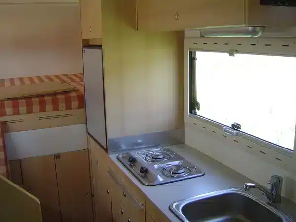 Kompakte Camper-Küche mit Gasherd, Spüle und Bett im Landrover-Offroadmobil