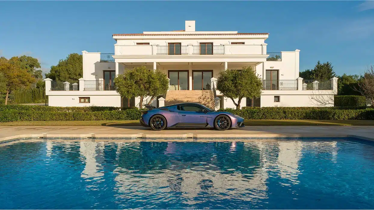Sportwagen steht vor einer eleganten Villa, im Vordergrund ein Swimmingpool.