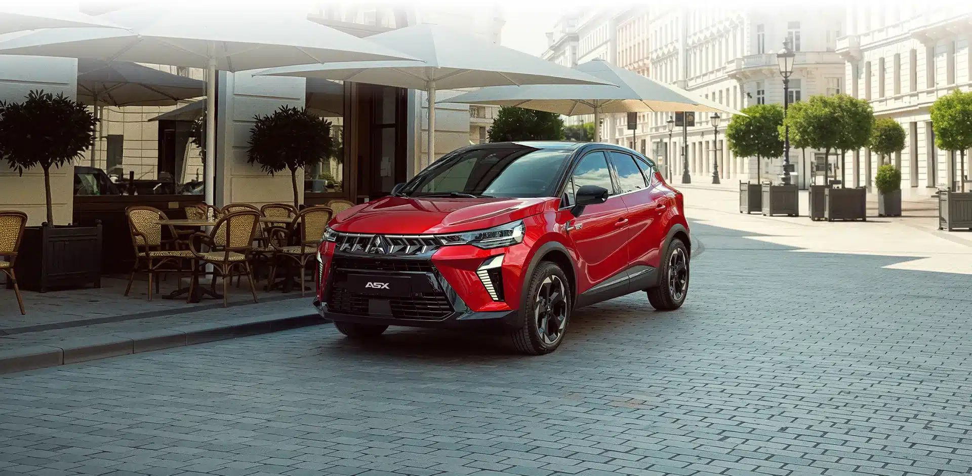 Roter Mitsubishi ASX SUV auf einer gepflasterten Straße vor einem Straßencafé in der Stadt