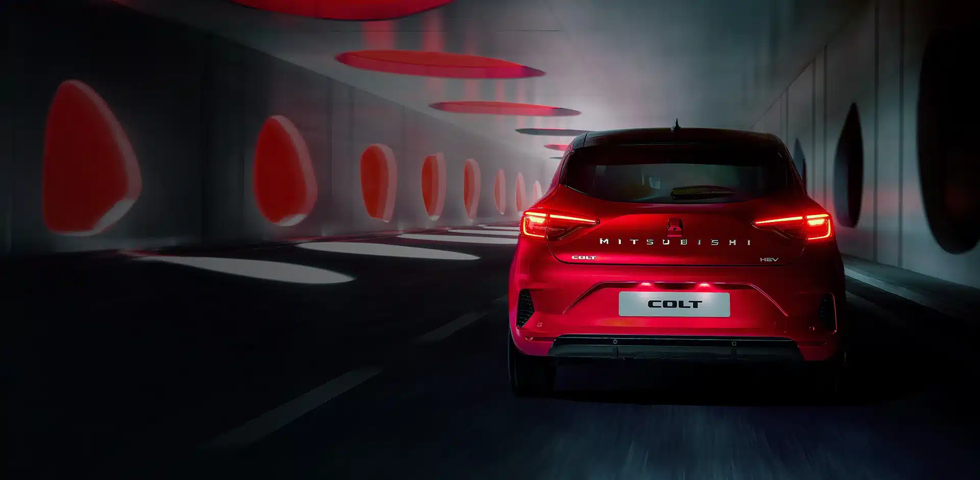 Heckansicht eines roten Mitsubishi COLT in einem futuristischen Tunnel mit leuchtenden Rücklichtern.