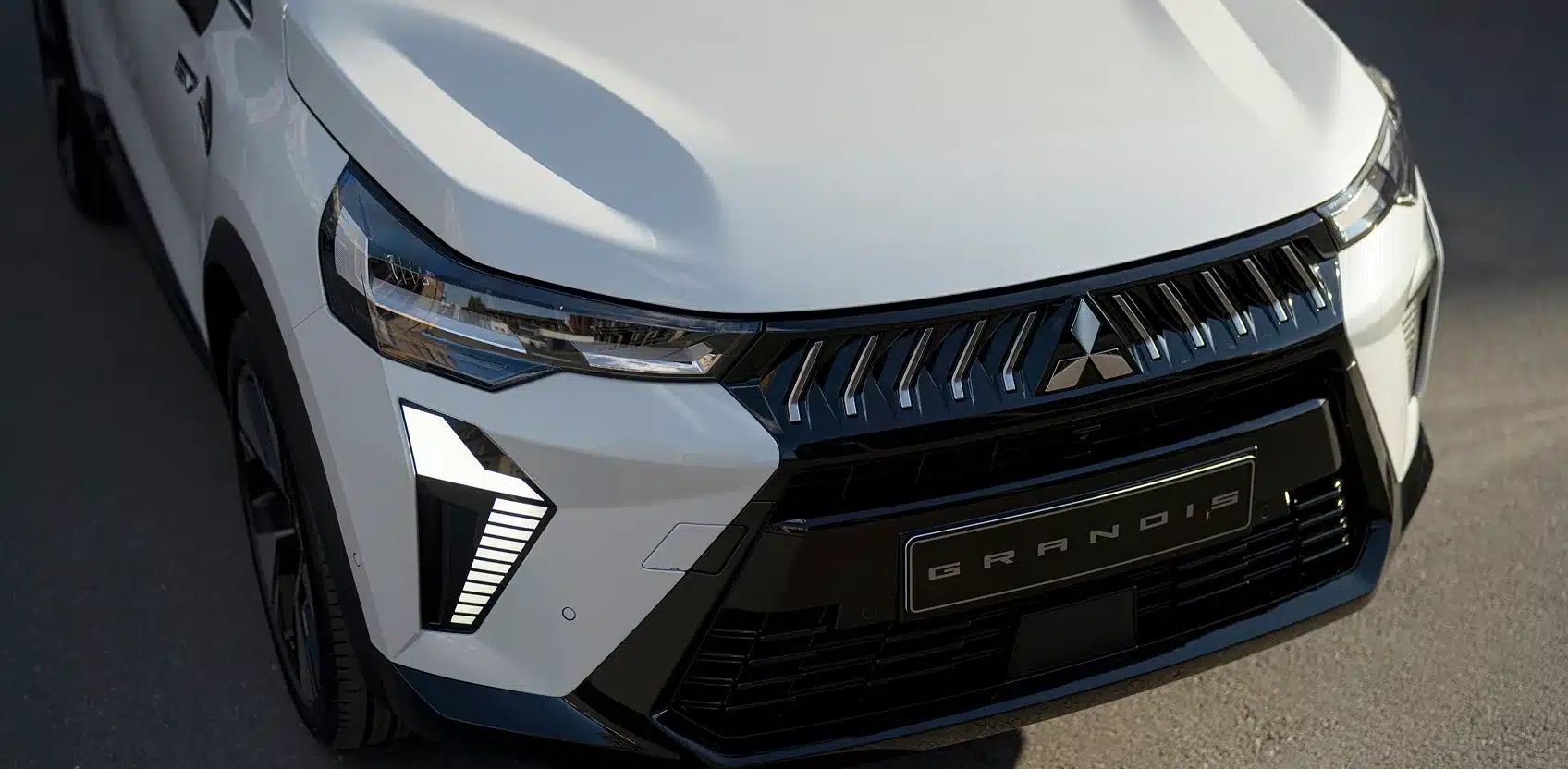 Front des Mitsubishi Grandis SUV mit Mitsubishi-Logo und modernen LED-Leuchten.