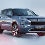 Mitsubishi Outlander Plug-in Hybrid in silberblauer Lackierung, von vorn schräg fotografiert auf heller Fläche.