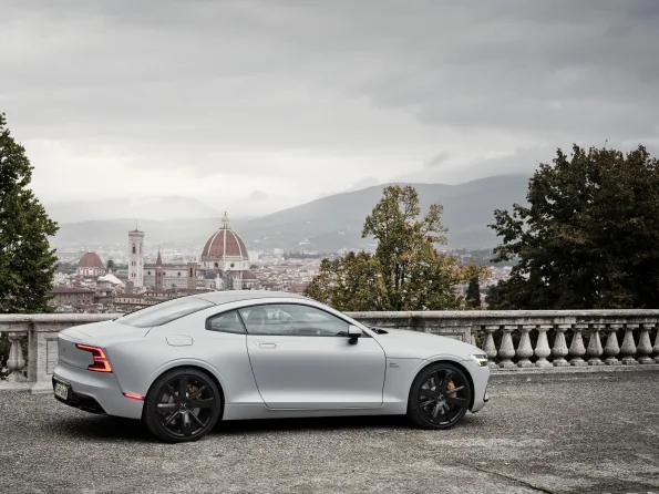 Polestar 1 Coupé in Silber seitlich fotografiert, im Vordergrund eine steinerne Balustrade, im Hintergrund die Stadt Florenz mit Dom.