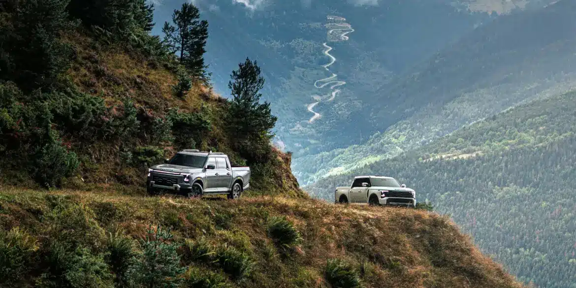 Zwei Santana 400 D Pick-ups im Offroad-Einsatz auf einem Bergweg mit Panoramablick ins Tal.