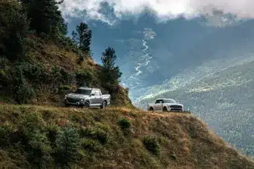 Zwei Santana 400 D Pick-ups im Offroad-Einsatz auf einem Bergweg mit Panoramablick ins Tal.