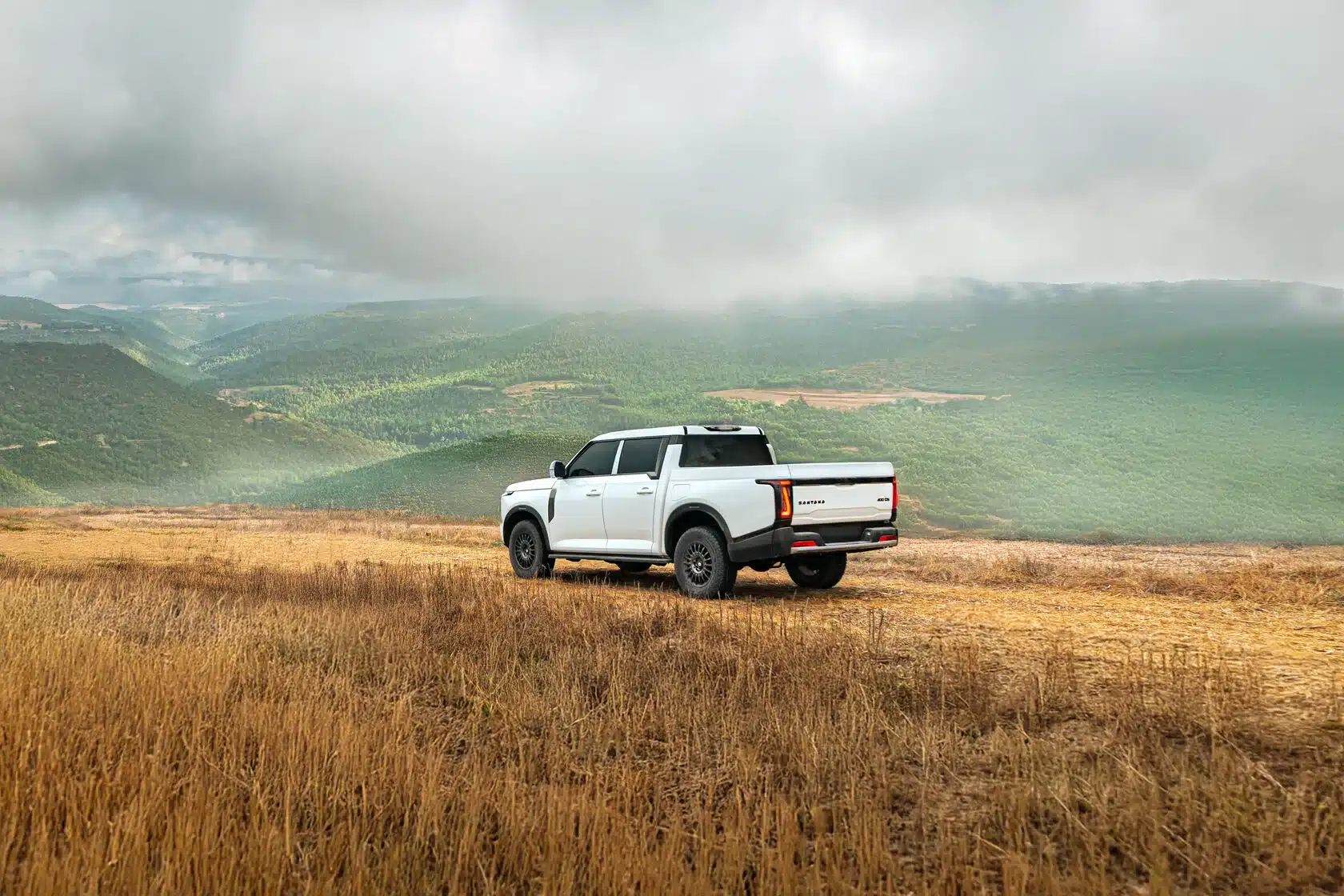 Weißer Santana 400 D Pick-up steht in einer weiten, hügeligen Landschaft auf einem Feldweg.