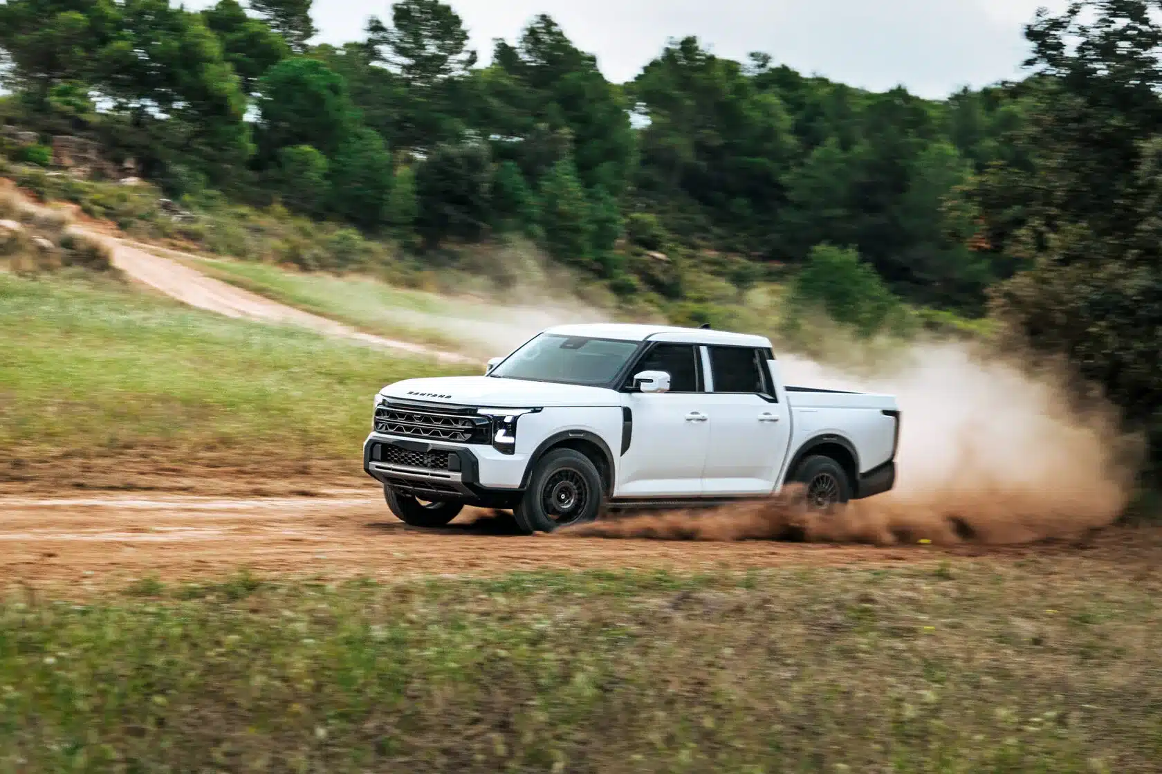 Der Santana 400 D Pick-up fährt dynamisch auf einer unbefestigten Straße und wirbelt Staub auf.
