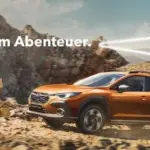 Subaru Crosstrek fährt über eine Schotterpiste in den Bergen, Outdoor-Prämienhinweis im Bild.