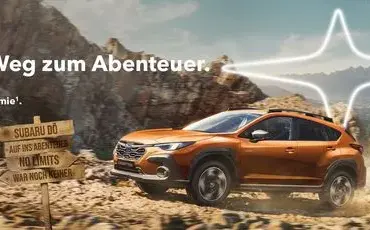 Subaru Crosstrek fährt über eine Schotterpiste in den Bergen, Outdoor-Prämienhinweis im Bild.