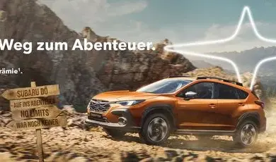 Subaru Crosstrek fährt über eine Schotterpiste in den Bergen, Outdoor-Prämienhinweis im Bild.