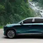 Togg T10X Elektro-SUV in blauer Lackierung vor einer natürlichen Waldkulisse, Seitenansicht.