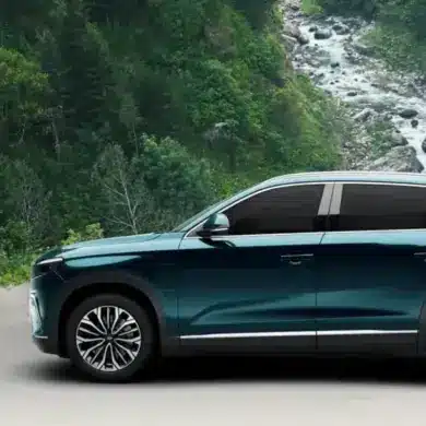 Togg T10X Elektro-SUV in blauer Lackierung vor einer natürlichen Waldkulisse, Seitenansicht.