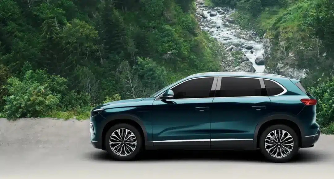 Togg T10X Elektro-SUV in blauer Lackierung vor einer natürlichen Waldkulisse, Seitenansicht.