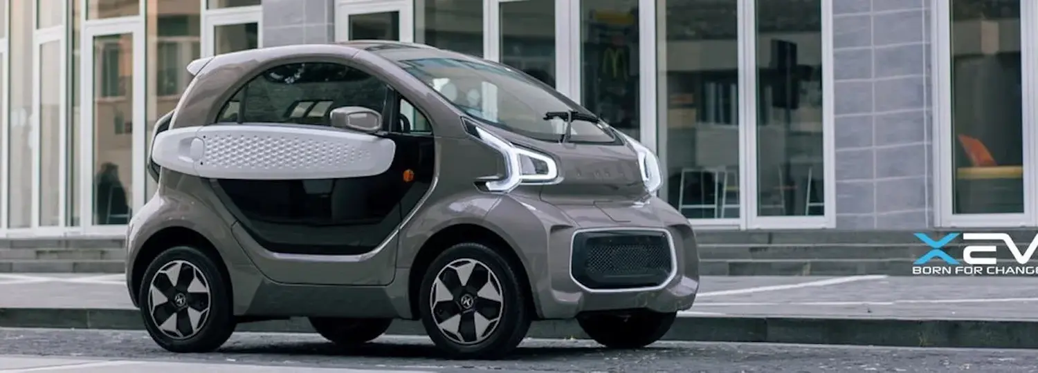 XEV YOYO, ein kleines, modernes Elektroauto für die Stadt, seitlich vor Gebäuden geparkt