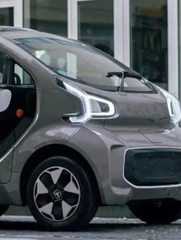 XEV YOYO, ein kleines, modernes Elektroauto für die Stadt, seitlich vor Gebäuden geparkt