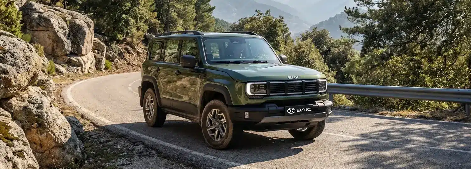 Grüner BAIC BJ40 D Pro SUV fährt auf einer kurvigen Bergstraße, umgeben von Felsen und Wald.