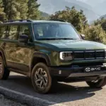 Grüner BAIC BJ40 D Pro SUV fährt auf einer kurvigen Bergstraße, umgeben von Felsen und Wald.