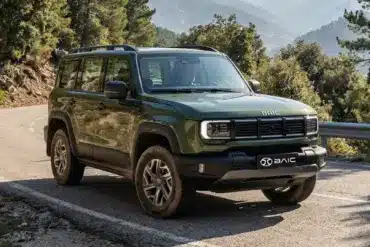 Grüner BAIC BJ40 D Pro SUV fährt auf einer kurvigen Bergstraße, umgeben von Felsen und Wald.