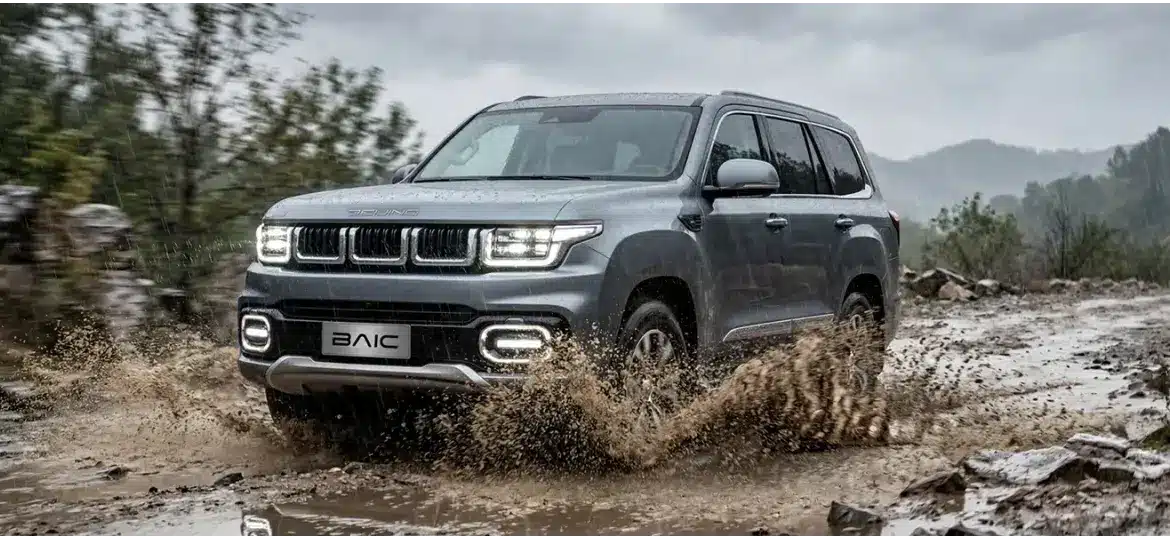BAIC BJ60 Flagship fährt bei Regen durch Matsch auf einer unbefestigten Straße im Gelände.