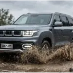 BAIC BJ60 Flagship fährt bei Regen durch Matsch auf einer unbefestigten Straße im Gelände.
