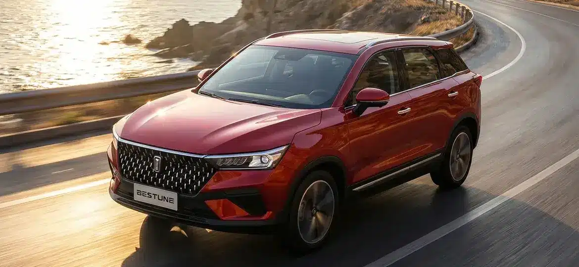 Bestune T77 Pro SUV in Rot fährt auf einer sonnigen Küstenstraße.