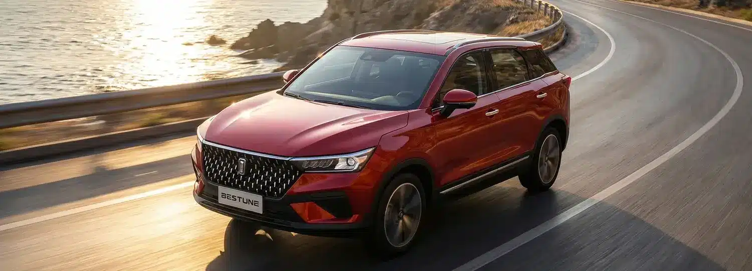 Bestune T77 Pro SUV in Rot fährt auf einer sonnigen Küstenstraße.