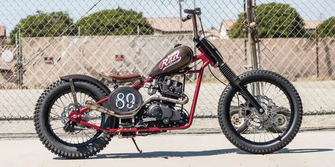 Seitenansicht einer modifizierten Cleveland CycleWerks Heist mit Starrrahmen und markanten Chopper-Elementen vor Maschendrahtzaun
